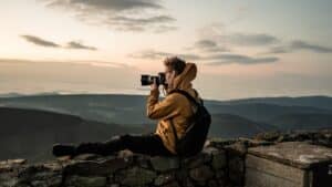 photographer sitting, taking a photo of a mountainscape