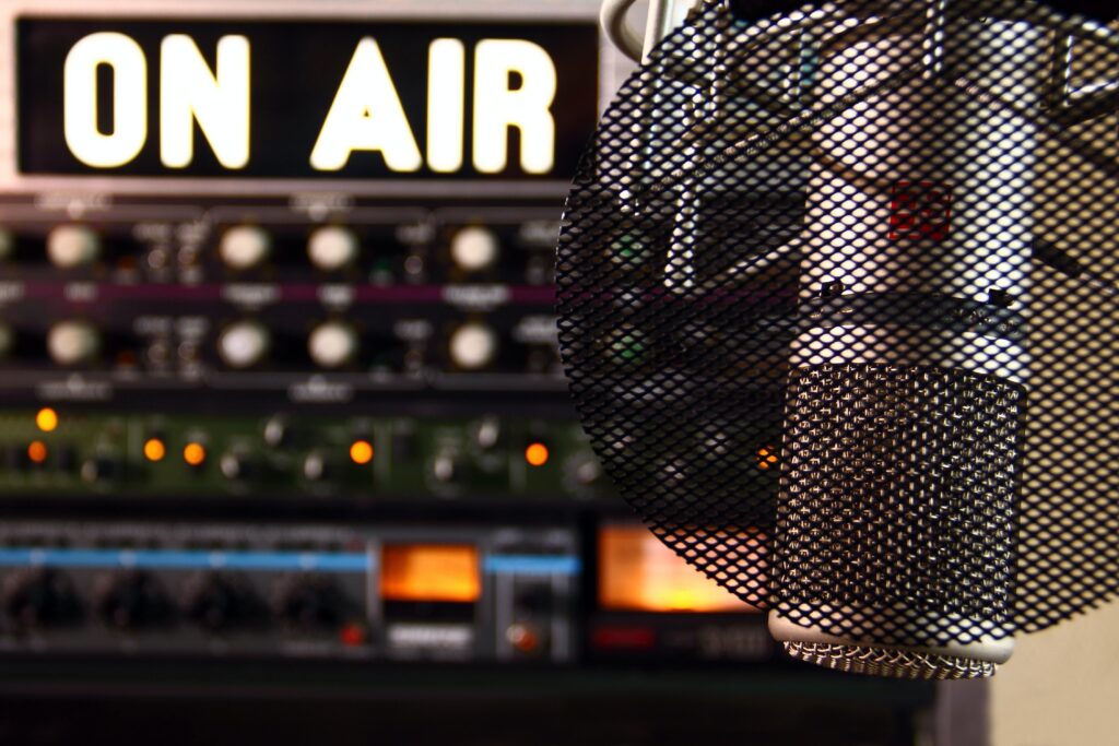 Large condenser microphone in center of image. Out of focus backdrop of a journalist's recording studio.