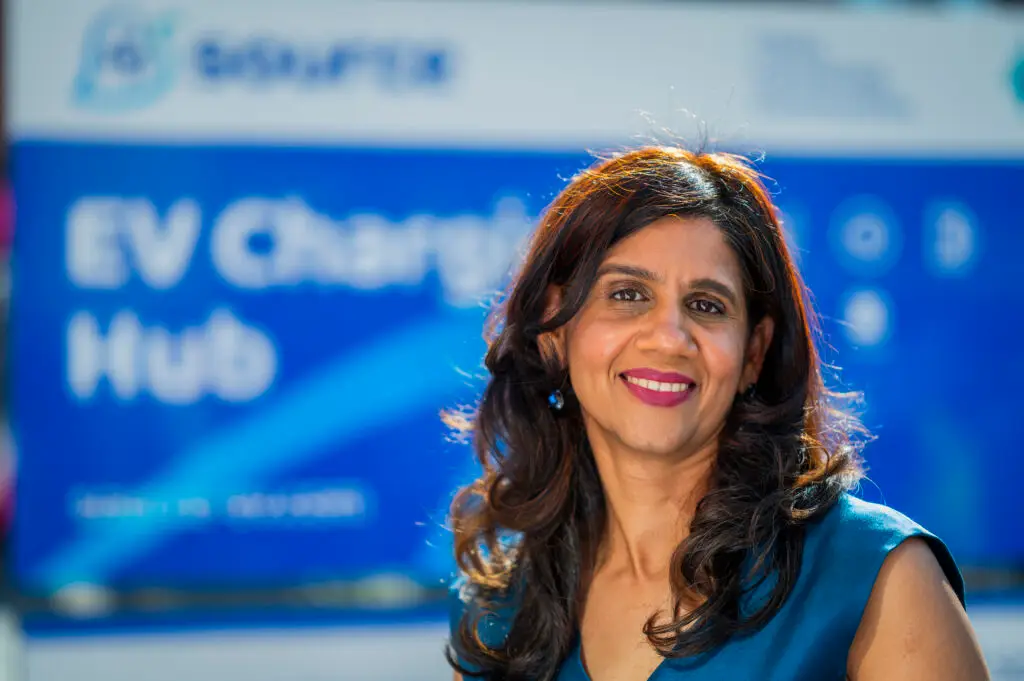 Deepa Chandrasekaran, Managing Director of Source, standing in front of EV charging hub branded backdrop at Maxim Park Eurocentral facility launch