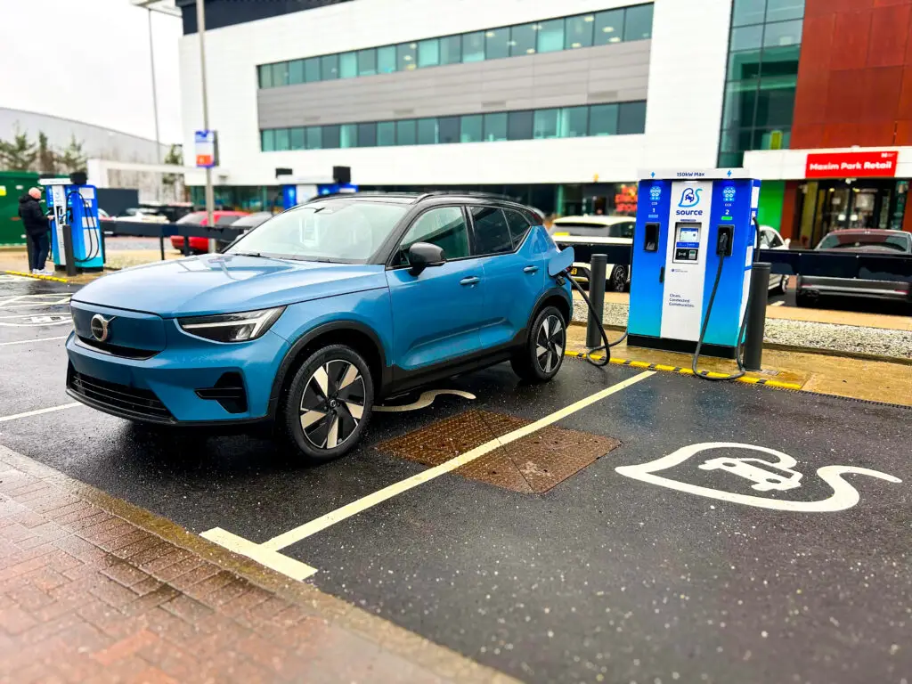 Blue Volvo electric vehicle charging at Source ultra-rapid 160kW charging station at Maxim Park Motherwell Eurocentral business park with modern office buildings in background