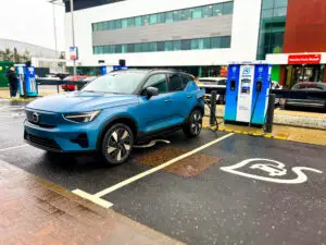 Blue Volvo electric vehicle charging at Source ultra-rapid 160kW charging station at Maxim Park Motherwell Eurocentral business park with modern office buildings in background