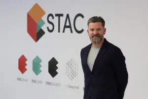 Paul Wilson Paul Wilson, CEO and Co-Founder of STAC, stands in front of the STAC logo and brand wall at thebeyond technology hub in Glasgow, featuring the STAC Scale, STAC Jobs, STAC Source and thebeyond sub-brand logos.