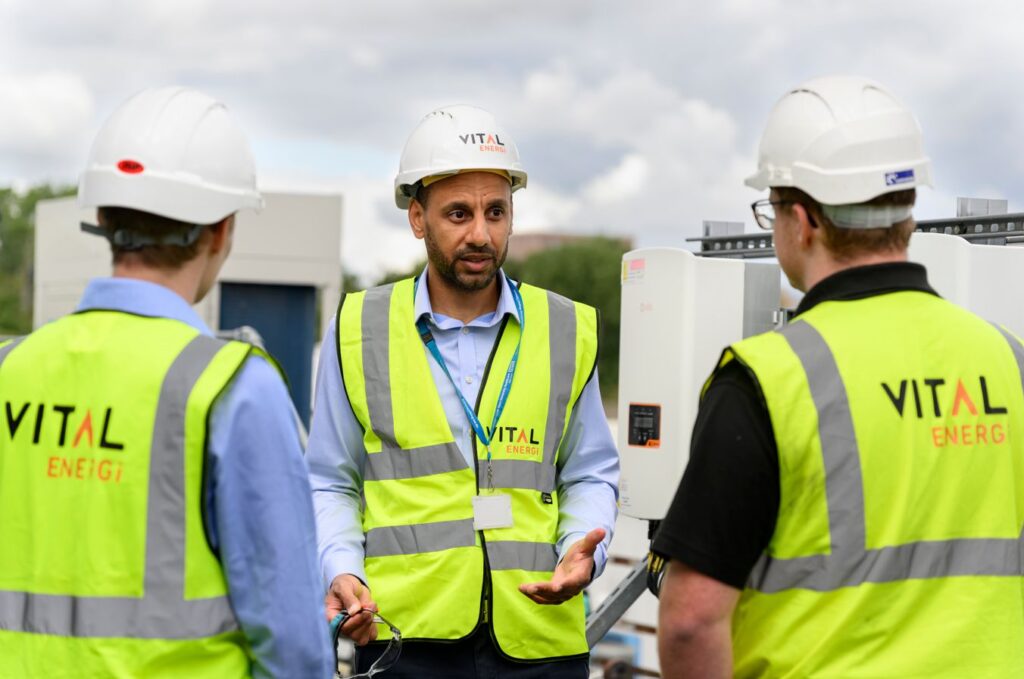 Vital Energi employees in hi-vis and hard hats discussing renewable energy equipment on site