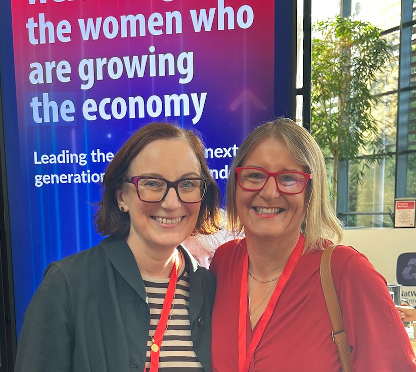 Wendy and Sarah Lee smiling together in front of a screen celebrating women growing the economy at a NatWest event, photo via Hot Tin Roof PR agency
