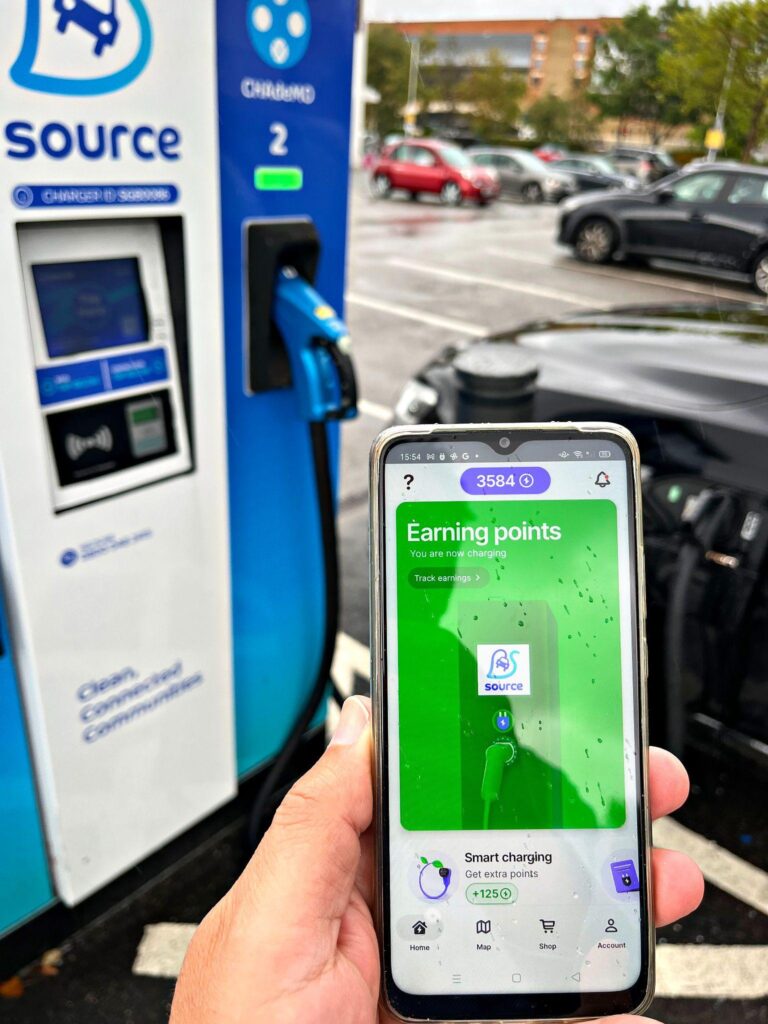 Driver holds a phone showing the PowerGoodies app earning points while charging at a Source ultra-rapid EV charger – Hot Tin Roof PR agency